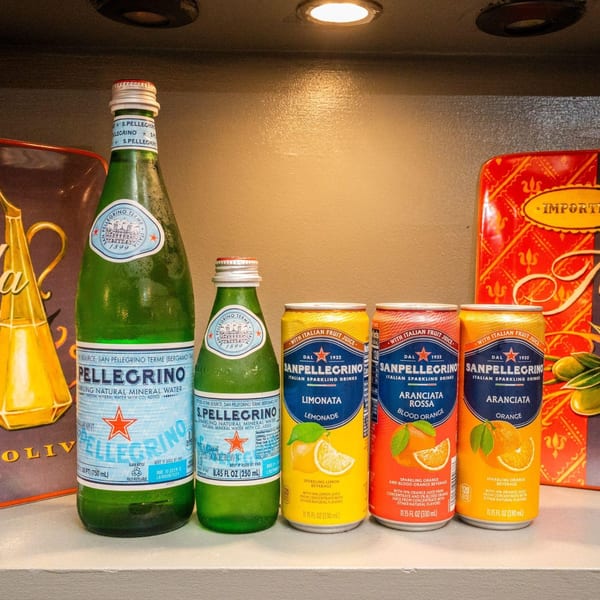 Assortment of San Pellegrino sparkling water bottles and flavored sparkling drink cans on a counter.