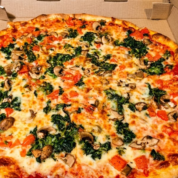 A large pizza with spinach, mushrooms, and tomatoes in a cardboard box.